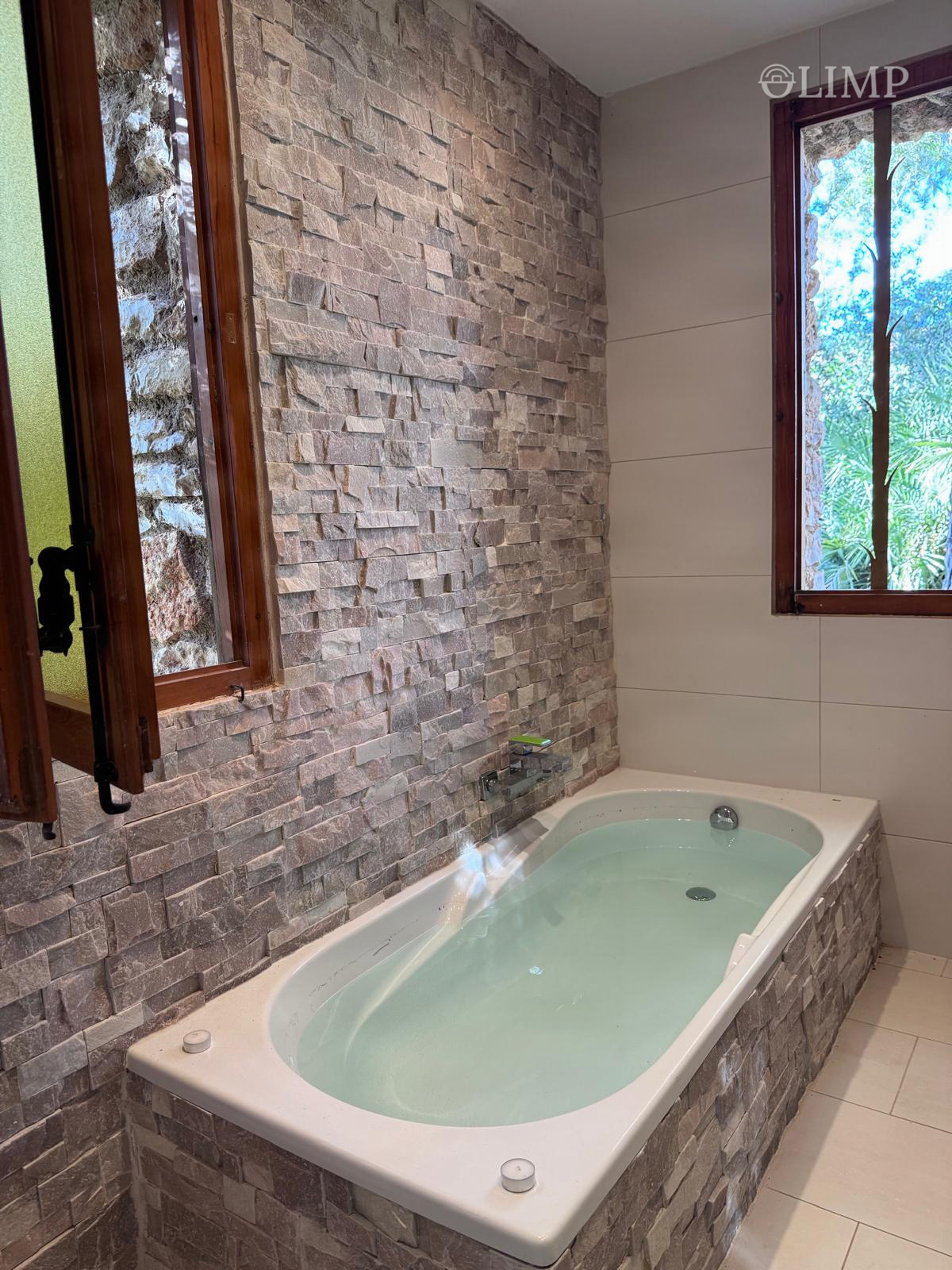 Baño con bañera junto a pared de piedra