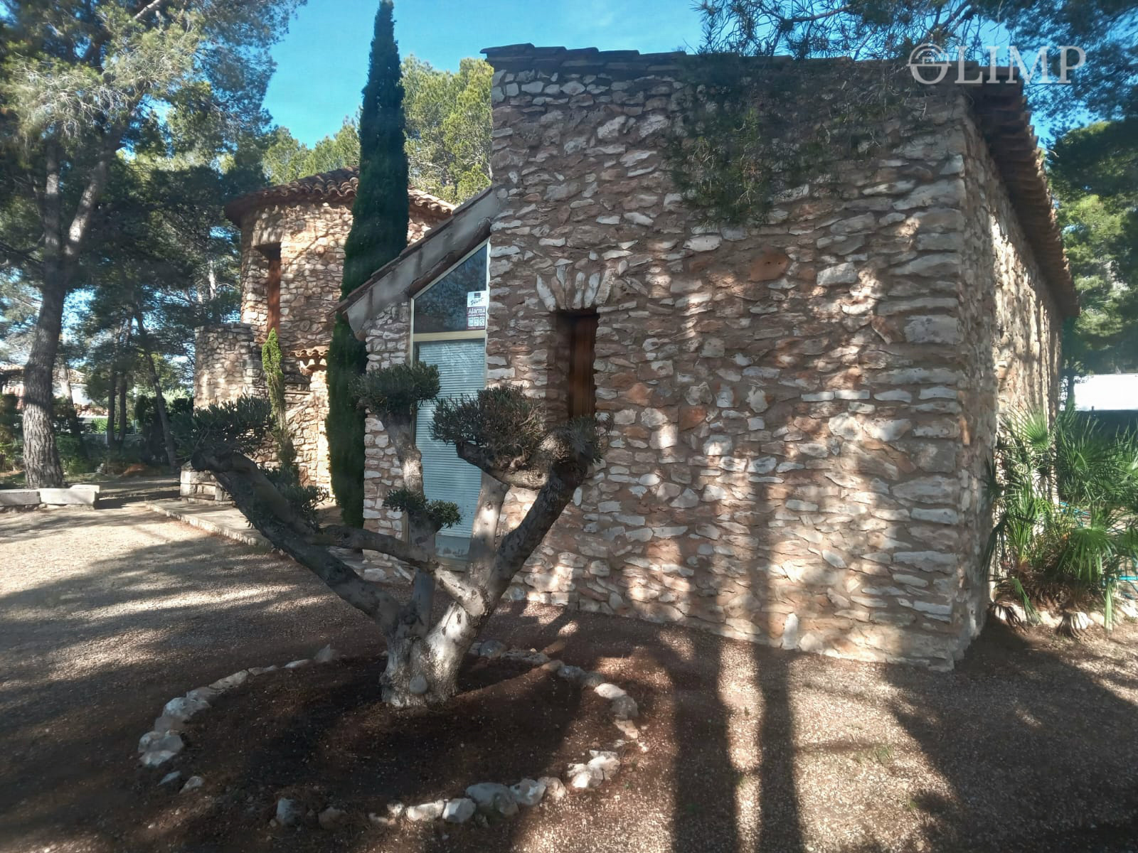 Fachada de piedra rodeada de jardín